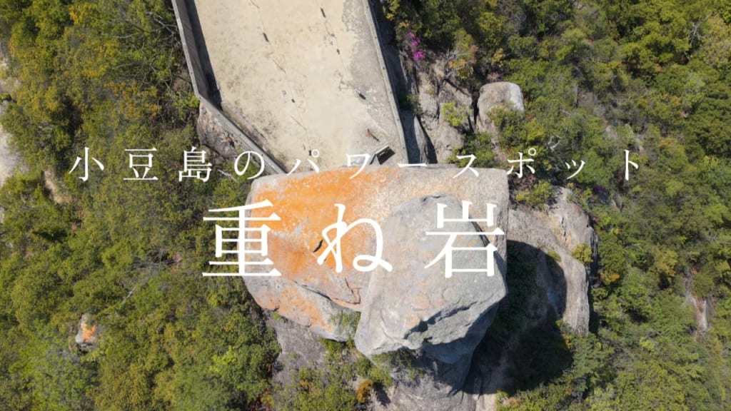 Aerial view of a large boulder with orange lichen in a forest, overlaid with Japanese title text.