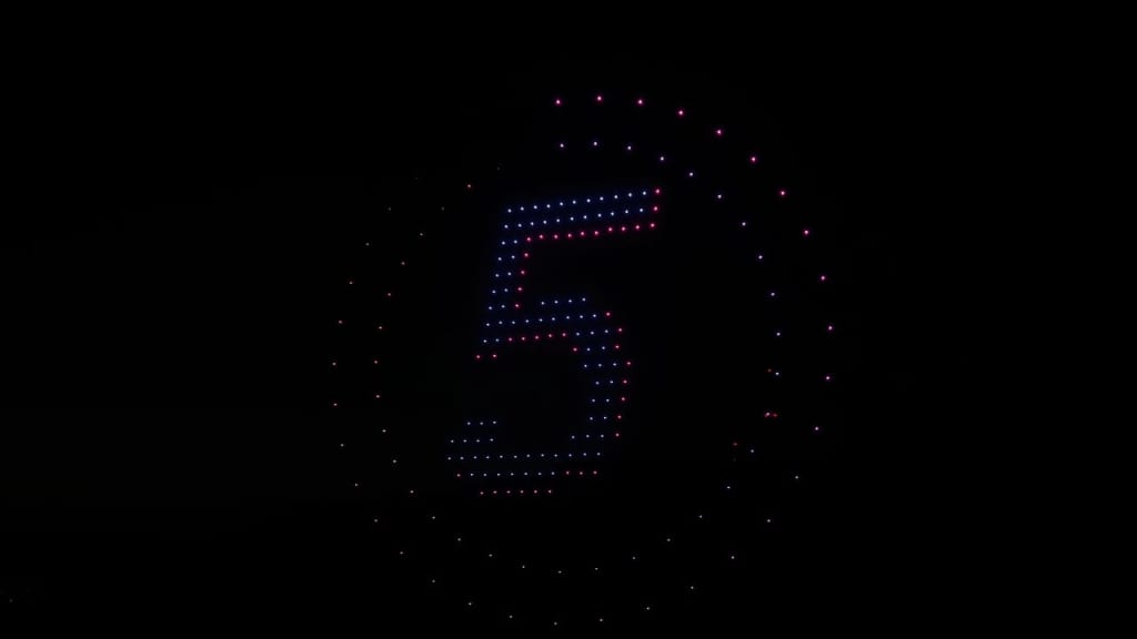 Circular ring of pink and blue LED dots forming the number 5 against a dark background, like a countdown display