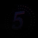 Circular ring of pink and blue LED dots forming the number 5 against a dark background, like a countdown display
