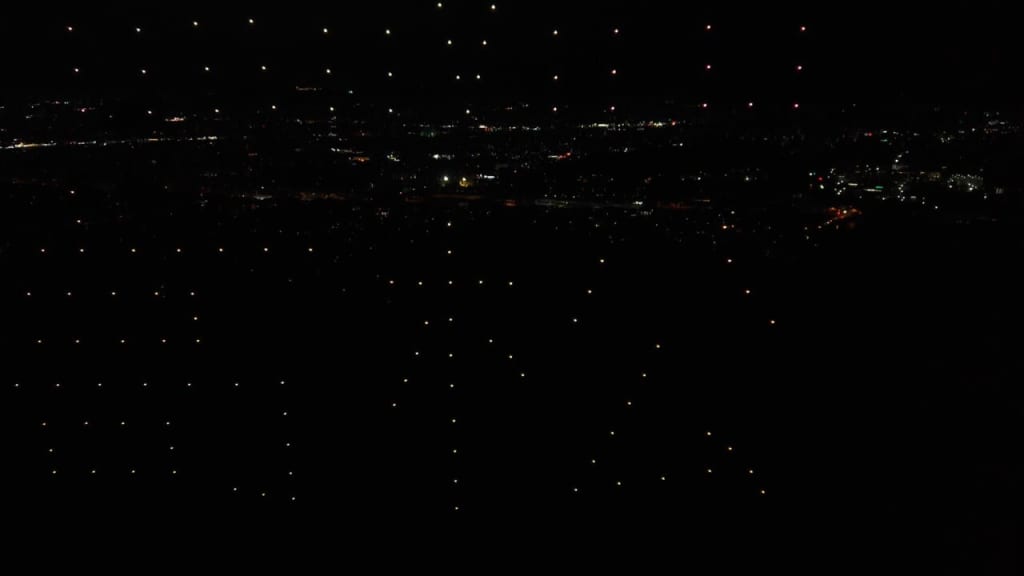 Night aerial view of a city with countless small lights dotting the dark landscape.