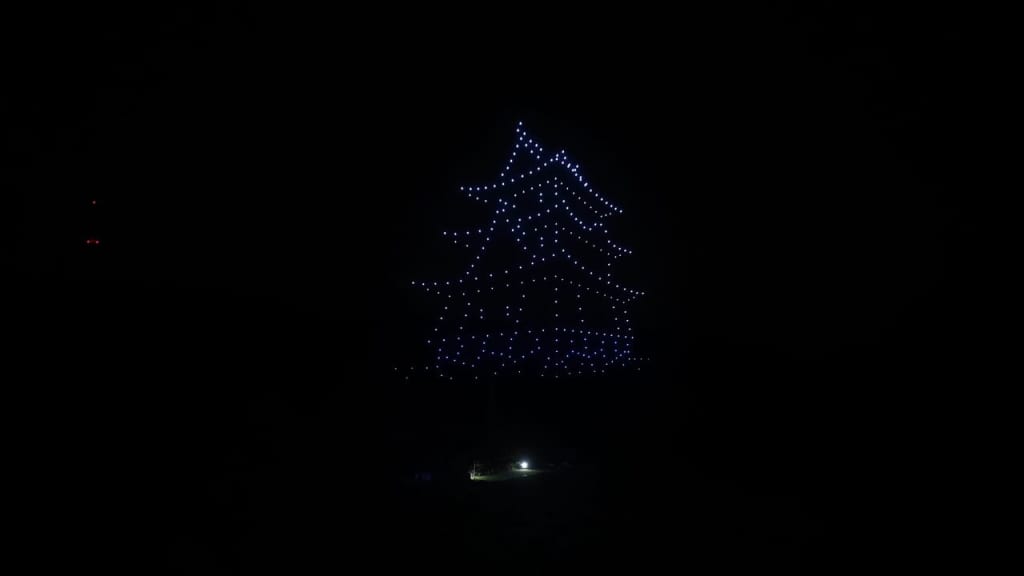 Blue-lit Christmas tree formed by hanging string lights against a dark night sky, glowing softly.