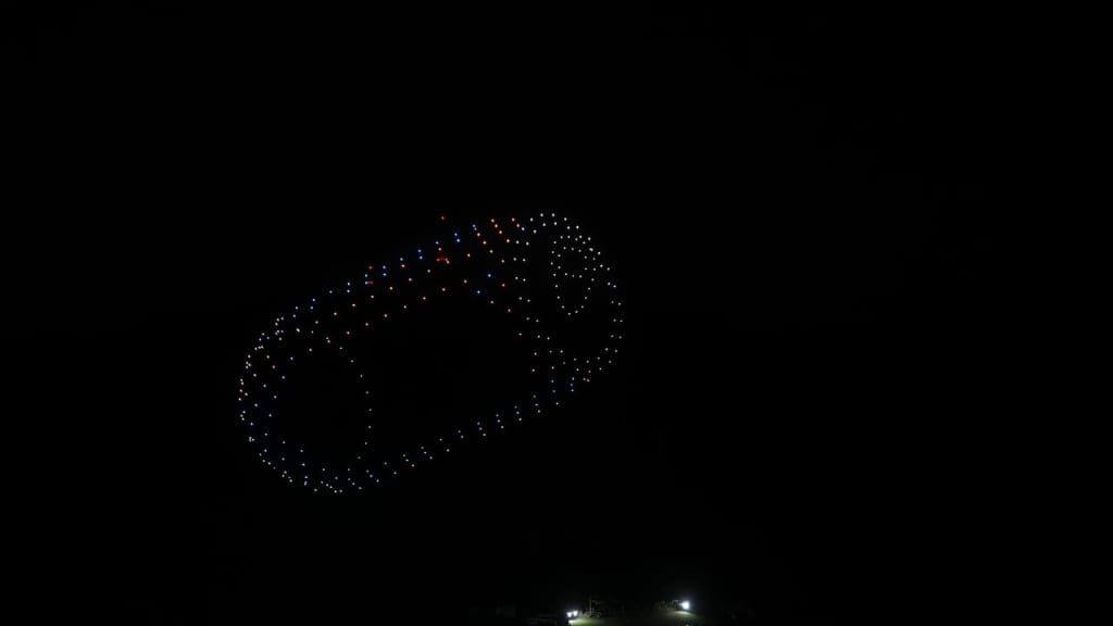 Donut-shaped ring of small blue, white, and red lights glowing in the dark night sky, seen from the ground.