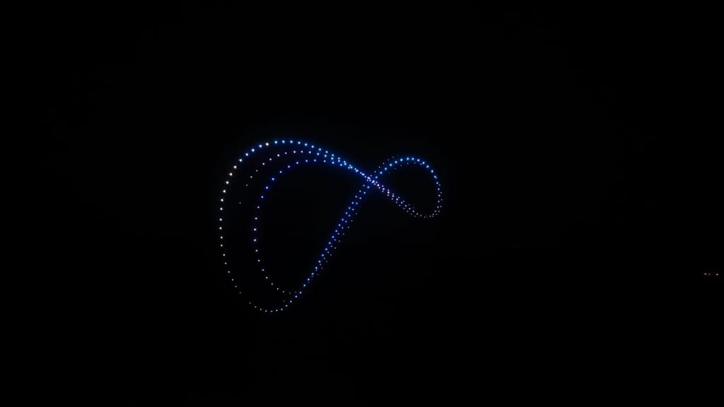 Blue LED light painting forming an infinity loop against a dark night sky, graceful swirling pattern of dots in blue tones