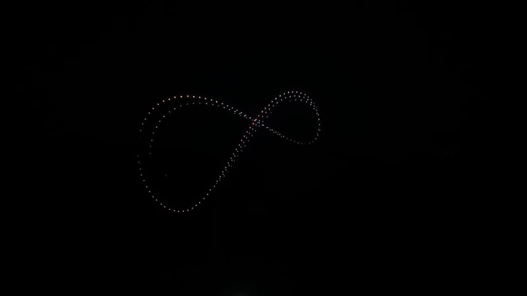 Dotted light trail forming an infinity symbol against a black night background.