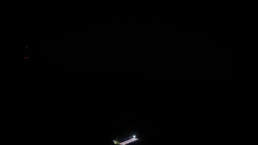 A brightly lit sports field or stadium at night, surrounded by darkness.