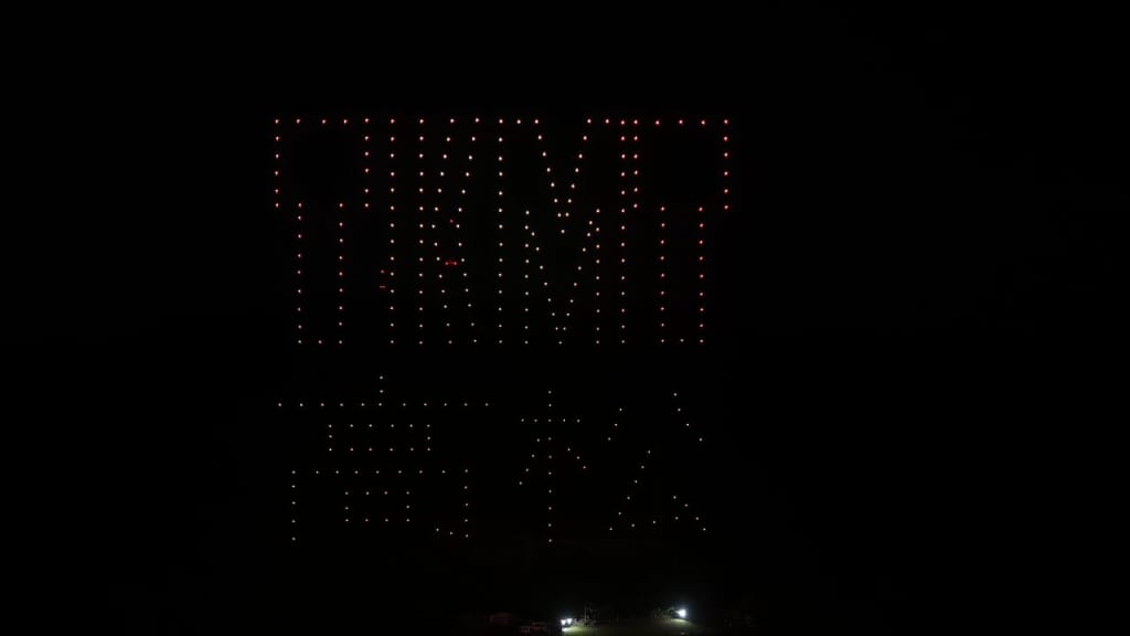 Large red LED dot matrix displaying the word TIME against a dark night sky, with a ground-lit base below.