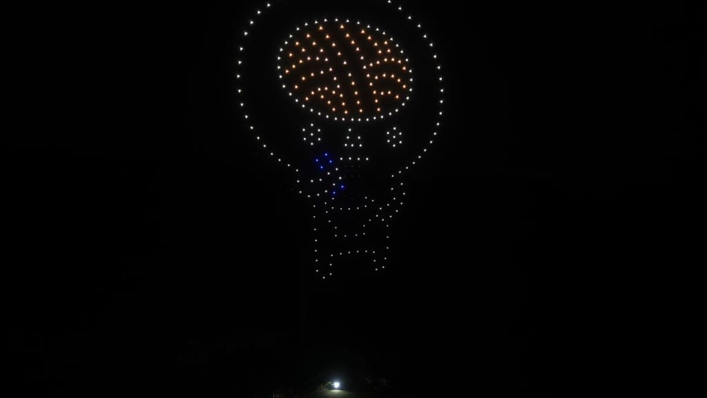 LED skull sculpture formed by glowing dots in a dark night, with orange brain area and white jaw outline.
