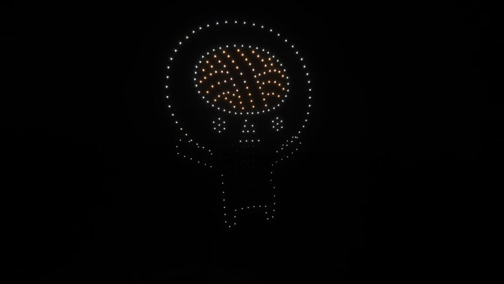 LED light-bulb sculpture made of small white LEDs with an orange brain-like center glowing in the darkbereich