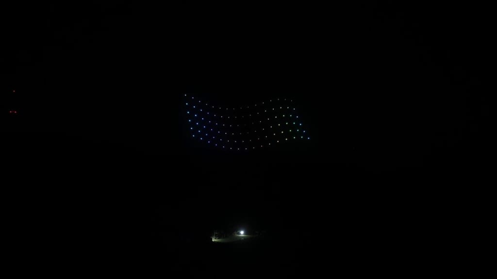 Dark scene with a curved row of small multicolored LED lights forming a rainbow arc in the distance.