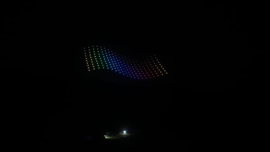 Curved panel of multicolored LED dots glowing in the dark, forming a rainbow arc above a dim landscape.