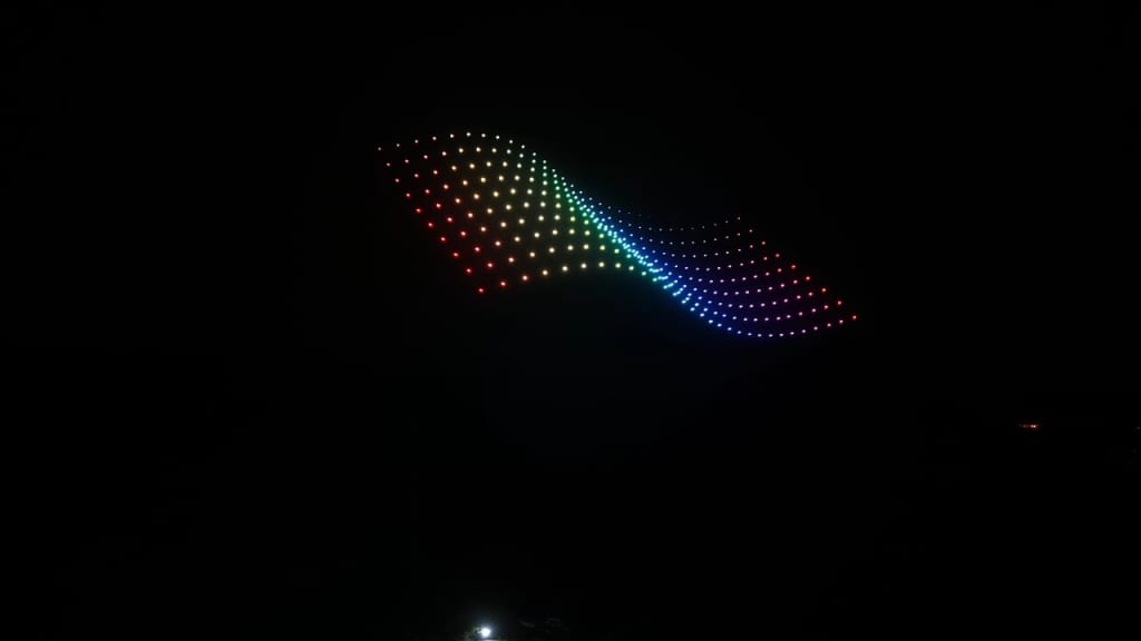 Curved rainbow LED light ribbon shining in the dark sky.