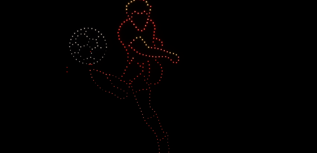 LED light art of a person kicking a ball, outlined in red and white/yellow dots on a black background